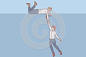 Business man extends helping hand to colleague who is falling into abyss, showing support