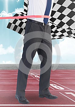 Business man at finish line on track against sky and checkered flag