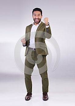 Business man, fist pump and celebrate success or winning portrait in studio on a gray background. Asian male