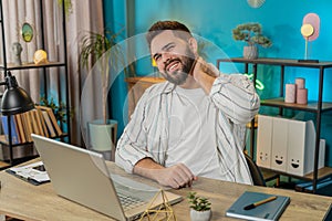 Business man freelancer overworking suffers from spine neck muscle pain at home office workplace