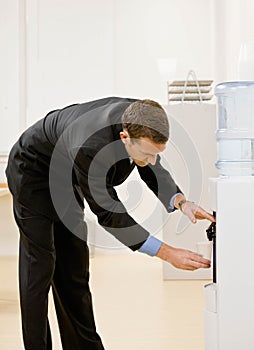 Business man gets water from water cooler