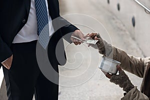 Business man give money to beggar