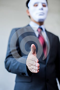Business man giving dishonest handshake hiding in the mask - Business fraud and hypocrite agreement photo