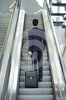 Business man going up escalator with bag