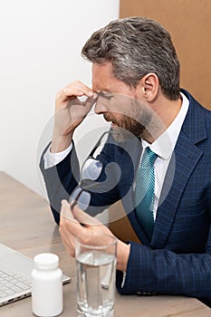 Business man got migraine touches her head because of pain. Man manager with strong headache working on laptop