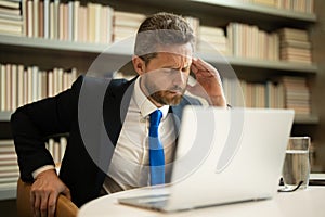 Business man got migraine touches her head because of pain. Man manager with strong headache working on laptop