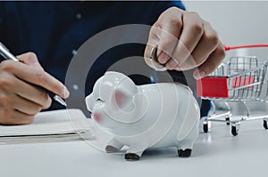 Business man hand holding coin money saving at piggy bank.Business economy management finance investment market and shopping