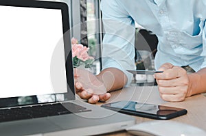 Business man hand holding credit card  with computer laptop on table.Shop online and make payment transactions business concept