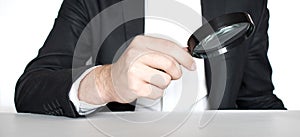 Business man hand holding magnifier for inspection on white background