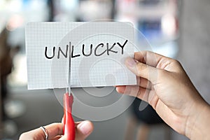 Business man hand holding red scissors and cutting white paper with the text Unlucky, change word to Lucky. challenge, positive