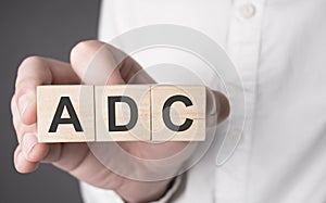 Business man hand holding wooden cube with adc text. Financial, marketing and business concepts photo