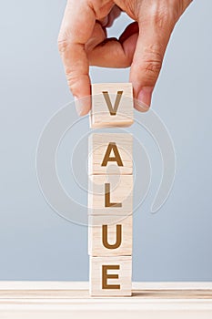 Business man hand holding wooden cube block with Value business word on table background. Mission, Vision and core values concept