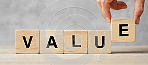 Business man hand holding wooden cube block with Value business word on table background. Mission, Vision and core values concept