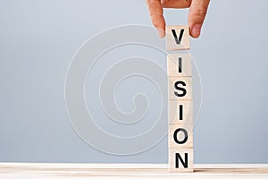 Business man hand holding wooden cube block with VISION business word on table background. strategy, Mission and core values
