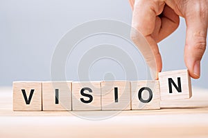 Business man hand holding wooden cube block with VISION business word on table background. strategy, Mission and core values