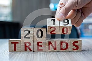 Business man hand holding wooden cube with flip over block 2019 to 2020 Trends word on table background. Resolution, strategy,