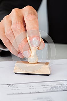 Business man hand pressing rubber stamp on document