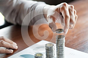 Business man hand putting coin stack for budget Saving money investment and financial accounting management or growing business co