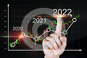 2022. business man hand touching virtual screen graphic graph chart diagram on dark background,