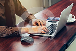 Business man hand using computer laptop in the office with sunlight. Vintage toned filter.