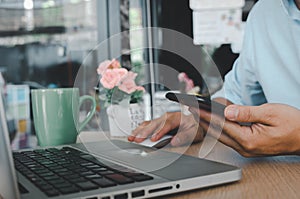 Business man hand using mobile smart phone and mouse computer laptop on table.searching internet technology. Social media online