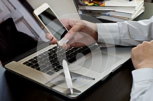 Business man hand using phone on laptop computer.