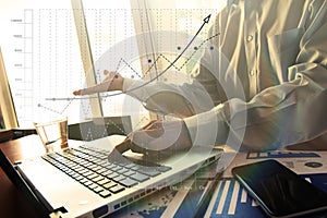 Business man hand working on laptop computer on wooden desk