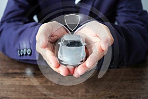 Business man hands holding car and shield icon , car insurance concept