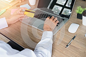 Business man hands holding a credit card and using laptop