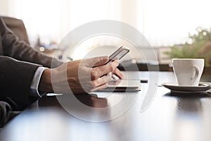 business man hands on a table with tablet, phone and cup of coffee in a office