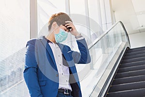 The business man has a headache while standing on the escalator from coronavirus and pm 2.5. Coronavirus and Air pollution pm 2.5
