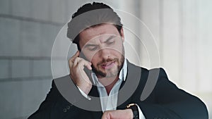 Business man having phone conversation. Executive checking time on wristwatch