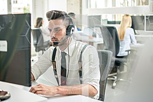 Business man with headset talking with customer while working on computer