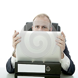 Business man hide behind laptop and documents