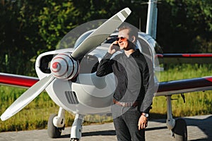 Business man with his airplanes. He is walking in the airport with the smart phone and making a call