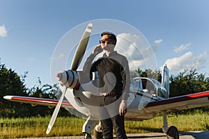 Business man with his airplanes. He is walking in the airport with the smart phone and making a call