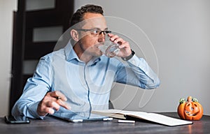 Business man at his desk drinking water in office