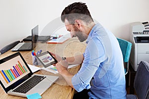 Business man at his desk using digital tablet and laptop