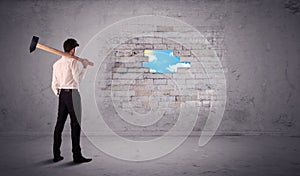 Business man hitting brick wall with hammer