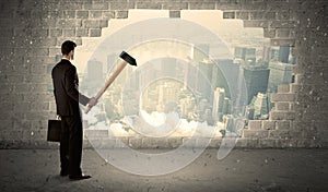 Business man hitting wall with hammer on city view