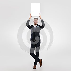 Business man holding blank white advertising billboard at studio