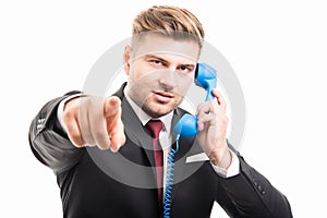 Business man holding blue telephone receiver pointing camera