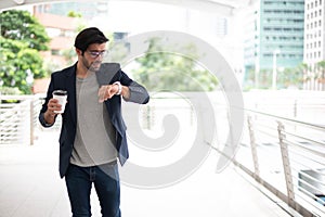 The business man holding a cup of coffee and looking the watch while hurry up go to work at the rush hour