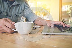 Business man holding a cup of coffee and using laptop, notpad on