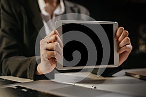 Business man holding digital tablet PC showing something on blank screen. Copyspace