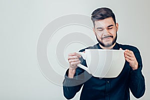 Business man holding a funny huge and oversized cup of black coffee in caffeine