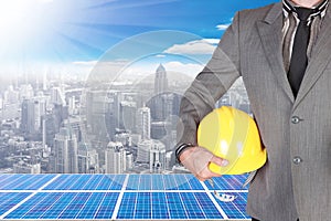 business man holding helmet and solar energy panels on high building against beautiful sky with in concept ecology and real estate