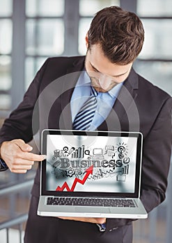 Business man holding laptop showing red arrow with black business doodles against blurry background