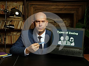 Business man holding laptop with written text Types of Zoning - closeup shot photo