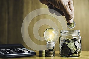 Business man holding light bulb on the desk in office and writing on note book it for financial,accounting,energy,idea concept